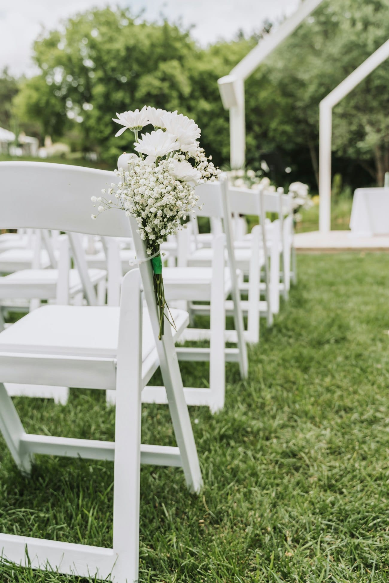 Allée de cérémonie bordée de chaises blanches fleuries