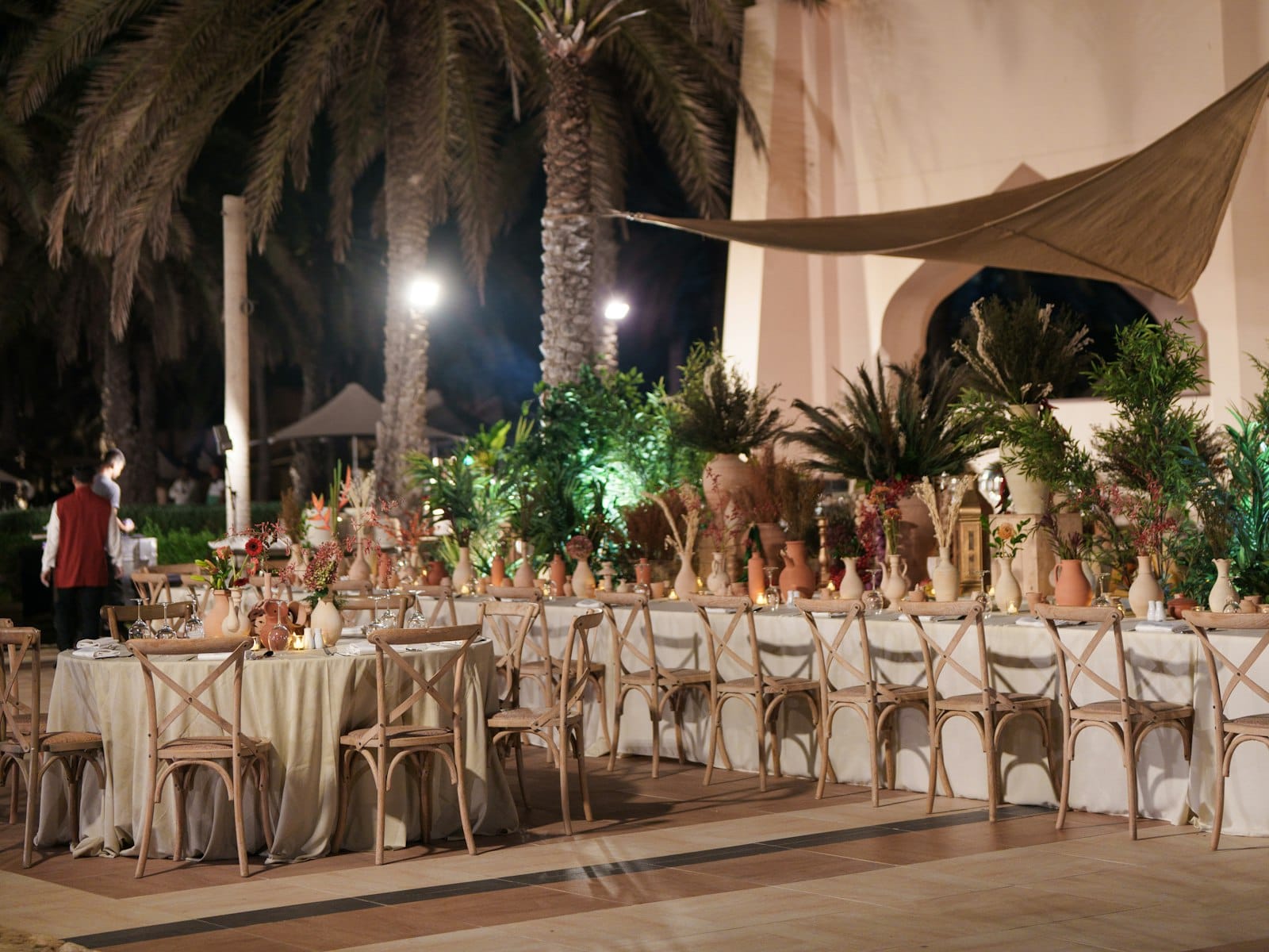 Dîner de mariage de nuit sous les palmiers, tables et chaises en bois